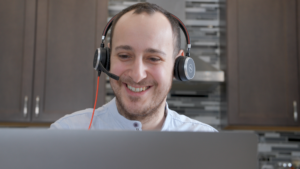Onat BAŞ working on site at Ross Video, smiling, wearing a headset on video call