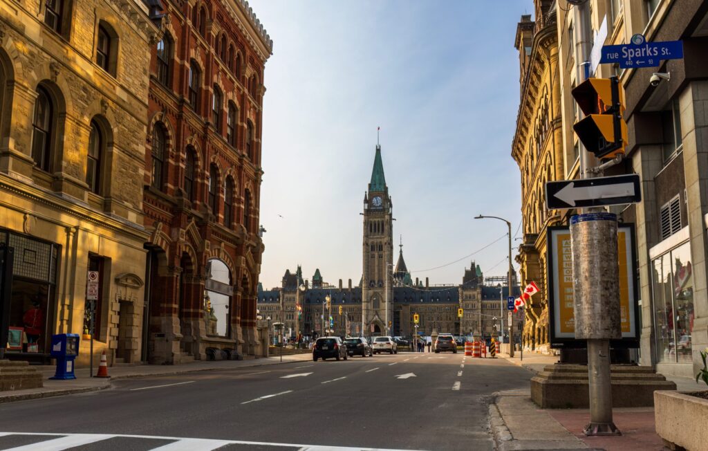 An image of Ottawa's Parliament Buildings as seen from the street between buildings on a sunny day.